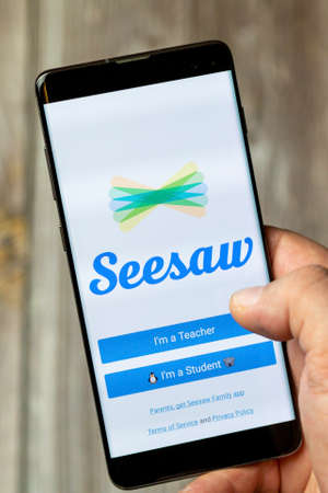 02-24-2021 Portsmouth, Hampshire, UK A mobile phone or cell phone being held by a hand with the Seesaw app open on screenのeditorial素材