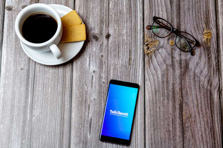 04-13-2021 Portsmouth, hampshire, UK A Mobile phone or cell phone laid on a wooden table showing the talk Remit app on screenのeditorial素材