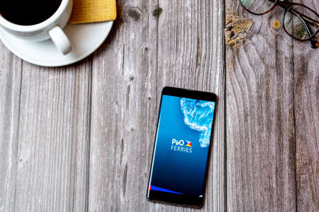 04-13-2021 Portsmouth, hampshire, UK A Mobile phone or cell phone laid on a wooden table showing the app on screenのeditorial素材