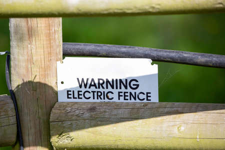 A warning sign on an electric fence on farmlandの写真素材