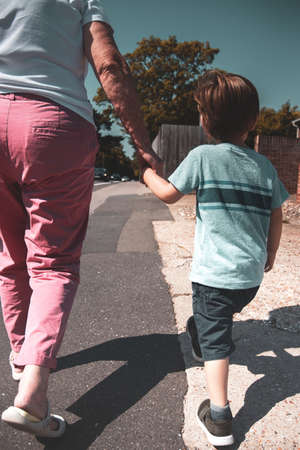 a child holding hands and being lead by a parent or grandparentの写真素材
