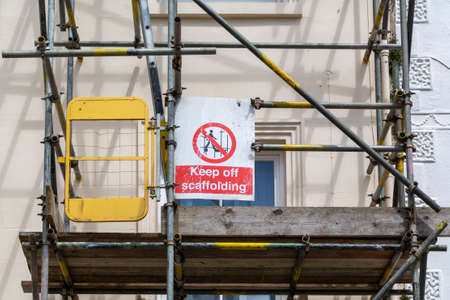 Scaffolding on the side of a building with a sign that reads Keep off scaffoldingの写真素材
