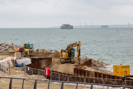 07-07-2021 Portsmouth, Hampshire, UK An excavator and a dumper working on coastal defences at Southsea in Portsmouth with the sea in the backgroundのeditorial素材