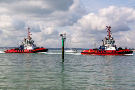 A pair of tug boats sailing into harbourの写真素材