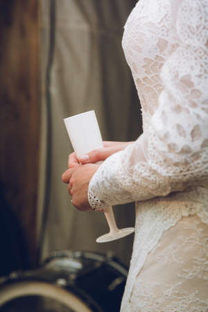 a bride in a wedding dress holding a champagne flute or wine glassの写真素材