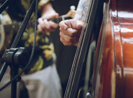 a closeup of a member of a bands hand playing a double bassの写真素材