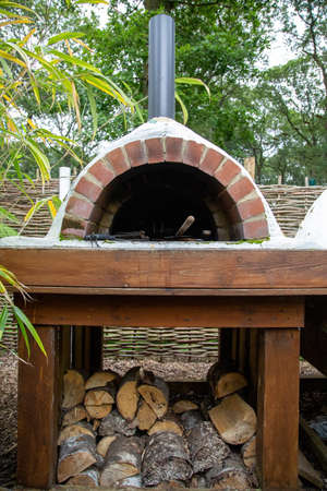 a pizza oven with logs stacked underneathの写真素材