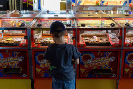 08-12-2021 Portsmouth, Hampshire, UK A Small boy playing the Coin Push arcade games in an amusements...