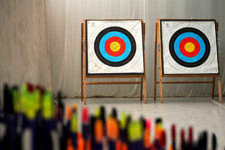 Archery arrows out of focus with targets in background