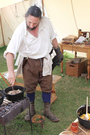 CORFE, DORSET,ENGLAND - AUGUST 06, 2015: A mediaeval re-enactor stirs an Old English recipe of pork andappleのeditorial素材