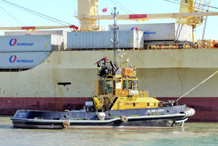 PORTSMOUTH, ENGLAND, MAY 29 2016: Tugboat SD Indulgent alongside a container ship
