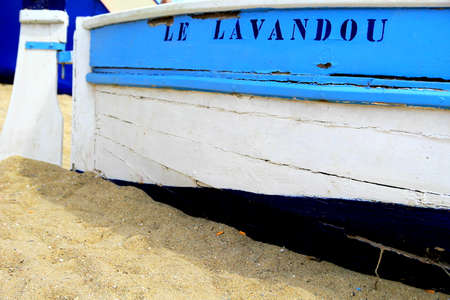 LE LAVANDOU, PROVENCE, FRANCE - AUGUST 17 2016: Colorful blue and white wooden boat on this French Riviera beach with the name of the town, Le Lavandou.のeditorial素材
