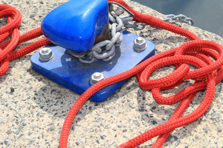 Closeup of blue harbour bollard with red rope on a concrete harbour quaysideの写真素材