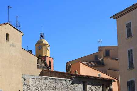 Belltower of Saint Tropez among traditional Provencal buildings with blue sky