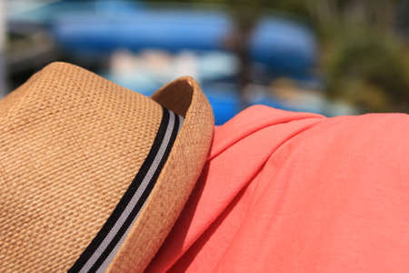 Straw trilby hat on sunny pool side with pink shirtの写真素材
