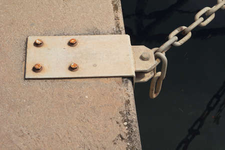 Steel mooring point on quayside with chain attached