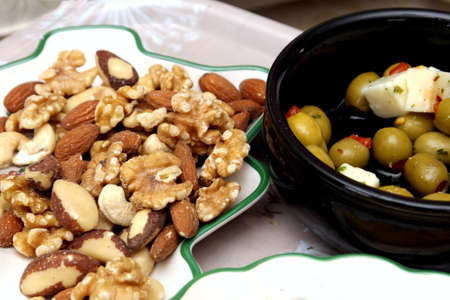 Olives, feta cheese, crisps, walnuts, almonds, cashew nuts, brazil nuts and hazelnuts served with an aperitifの写真素材