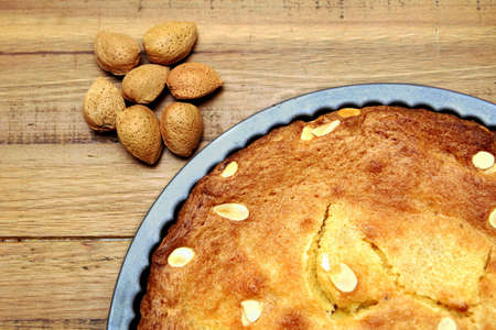 Unshelled almond nuts next to a freshly baked frangipane tart or cakeの写真素材