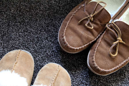 Overhead shot of generic ladies and mens slippers on a dark gray carpetの写真素材