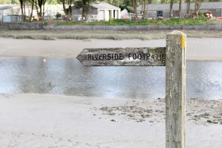 Wooden sign with river in distance, reading "Riverside Footpath"の写真素材
