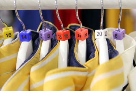 Closeup of various clothes size markers on a row of yellow jacketsの写真素材