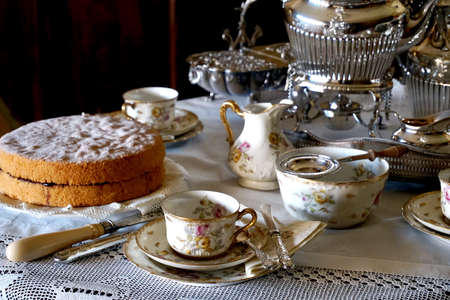 Fresh Victoria Sponge and tea making essentials on a traditional English tableの写真素材