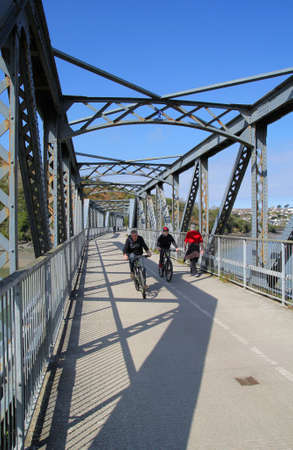 Camel Estuary, Cornwall, UK - April 4 2017: Cyclists on the disused iron railway bridge on the Camel Trail in Cornwallのeditorial素材