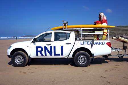 Newquay, Cornwall, UK - April 7 2017: Female RNLI lifeguard keeping watch on top of a truck on a surfing beach in Newquayのeditorial素材