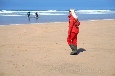 Newquay, Cornwall, UK - April 7 2017: Female RNLI lifeguard keeping watch on a surfing beach in Newquayのeditorial素材