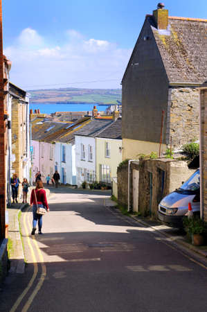 Padstow, Cornwall, UK - April 6th 2017: Cross Street, a quaint narrow road with sea view in the picturesque Cornish village of Padstow on a sunny day with blue skyのeditorial素材