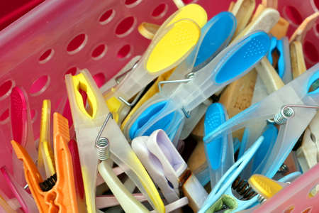 Closeup of brightly coloured clothes pegs or clothespins in a plastic containerの写真素材