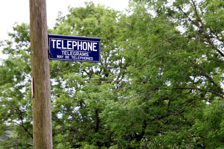 Dorset, UK - May 31st 2016: Vintage British telephone and telegram sign on a traditional wooden pole.のeditorial素材