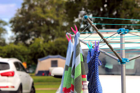 St Leonards, Hampshire, UK - May 30th 2017: Towel and swimsuit hanging on a rotary camping clothes drier on a campsite, with car, tent and caravan in the backgroundのeditorial素材