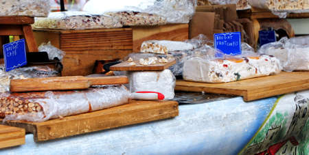 Market stall selling hand made nougat on traditional wooden boards, flavored with "Cafe" (coffee) and "Fruit confis" (candied fruit).の写真素材