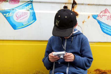 Lee-on-the-Solent, Hampshire, UK - June 10 2017:  Young boy in baseball cap checks the photos on his cameraのeditorial素材