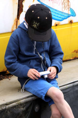Lee-on-the-Solent, Hampshire, UK - June 10 2017:  Young boy in baseball cap checks the photos on his cameraのeditorial素材
