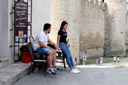 Carcassonne, Languedoc-Roussillon, France - August 24 2017: Young couple taking a cigarette break outside a cafe in the historic fortified city of Carcassonne in Languedoc Franceのeditorial素材