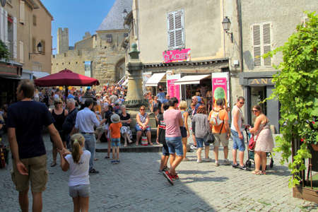 Carcassonne, Languedoc-Roussillon, France - August 24 2017: Tourists relaxing in the sunshine along a cobbled street in the medieval French fortified city of Carcassonne, La Cite, Languedoc-Roussillon, Franceのeditorial素材