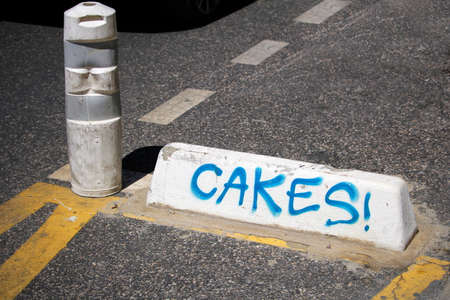 Sete, Herault, France  - Aug 21 2017: Traffic control bollard and concrete block with the word "Cakes!" written in spray paintのeditorial素材