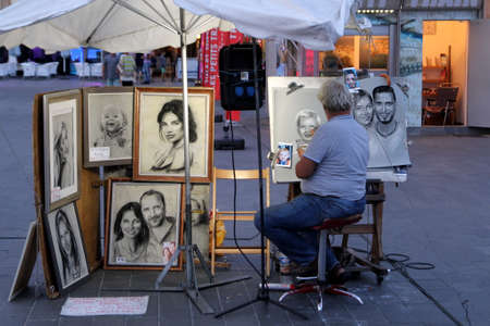 Cap D'Agde, Herault, France - August 30 2017: A street artist working in charcoal and chalk draws a portrait of a young young child in in the port town of Cap D'Agde, Languedoc, Franceのeditorial素材