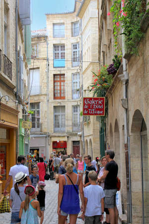 Pezenas, Herault, France - Aug 26 2017: Busy narrow traditional street of stone buildings, full of tourists, in Pezenas, Languedoc, Franceのeditorial素材