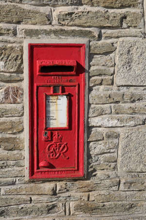 Porth, Cornwall, UK - April 7 2018: ~Red British Royal Mail post box set into a stone wall, bearing the initials GR meaning King George.のeditorial素材