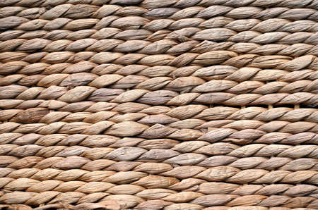 Background texture of beige or straw colored wicker or seagrass.