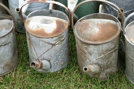 Group of old antique galvanized iron watering cans on grassの写真素材