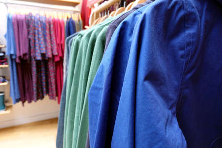 Shallow focus close up of a rack of blue and green clothes in a clothing store