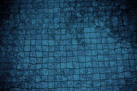 The tiles of a pool distorted through the water creating a pattern.