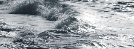 The setting sun creates a silver look to the water as it crashes to shore. Zanzibar, Tanzania.