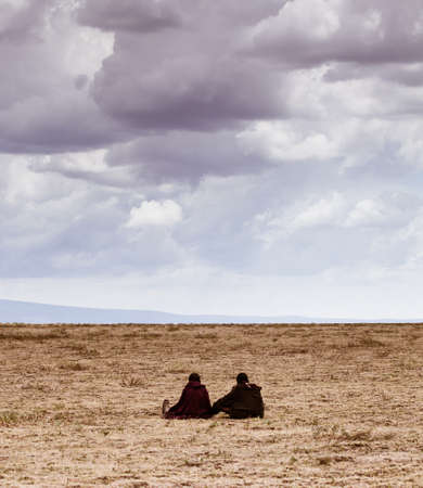 Masai children sit on the savannah looking out into the vast distance of the Serengeti plain  Tanzaniaの写真素材