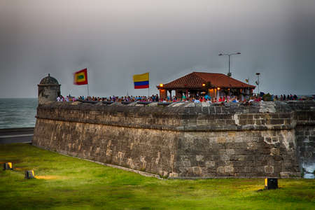 Tourists and local couples enjoy sundowners on the old city wall of Cartagena.の写真素材