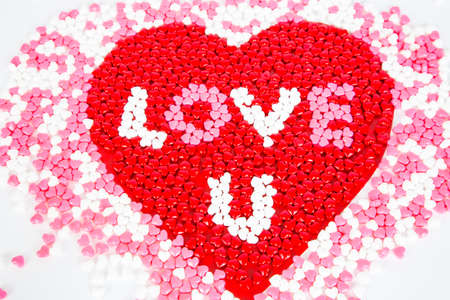 Red, WHite, and Pink candy hearts for Valentine's day, arrainged in a large heart on a white...